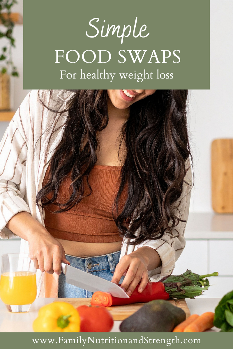 a woman cutting a carrot in the kitchen with a cup of juice